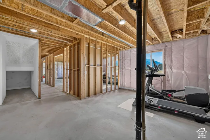 Unfinished interior space featuring exposed wood-stud framing, concrete flooring, recessed lighting, and fiberglass wall insulation
