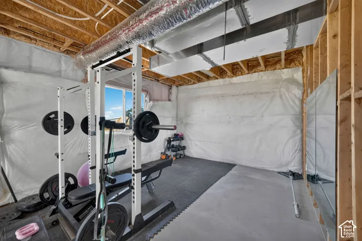 Unfinished room featuring exposed wooden joists, insulated walls, concrete flooring, and an exterior window
