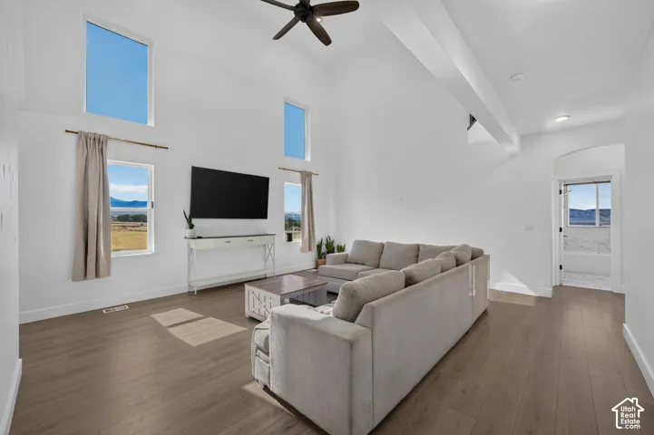 Vaulted ceilings with an integrated ceiling fan, wood-finish flooring, and expansive windows providing natural light