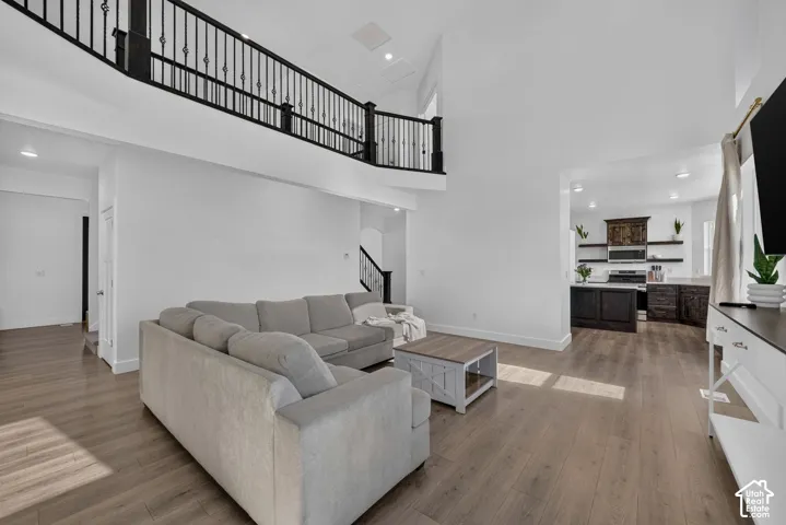 Vaulted ceilings, wood-finish flooring, and a decorative black iron railing along the upper-level loft