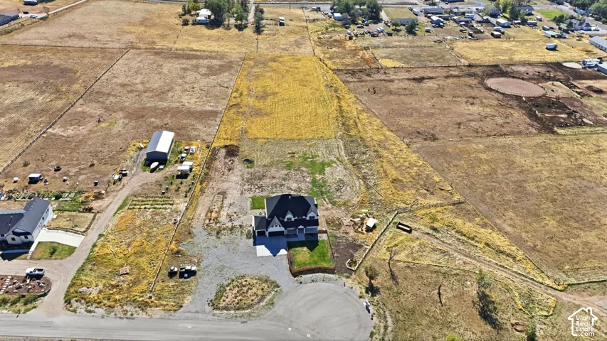 Aerial perspective of a multi-acre property featuring an expansive lot, a detached storage structure, and a multi-level residence with a multi-car garage
