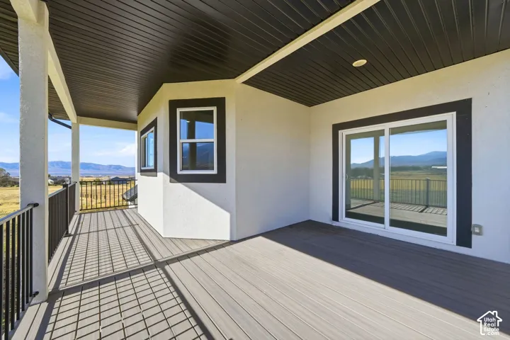 Covered deck featuring composite decking, black metal railings, and dual sliding glass doors