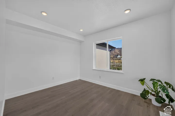 Neutral-toned room featuring wood-finish flooring, recessed lighting, and a single-pane window with mountain scenery