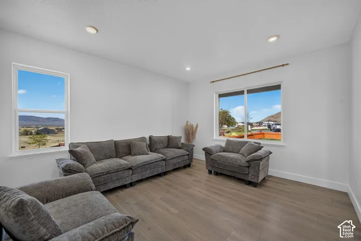Neutral interior space featuring wood-finish flooring, recessed lighting, and multiple windows with mountain scenery