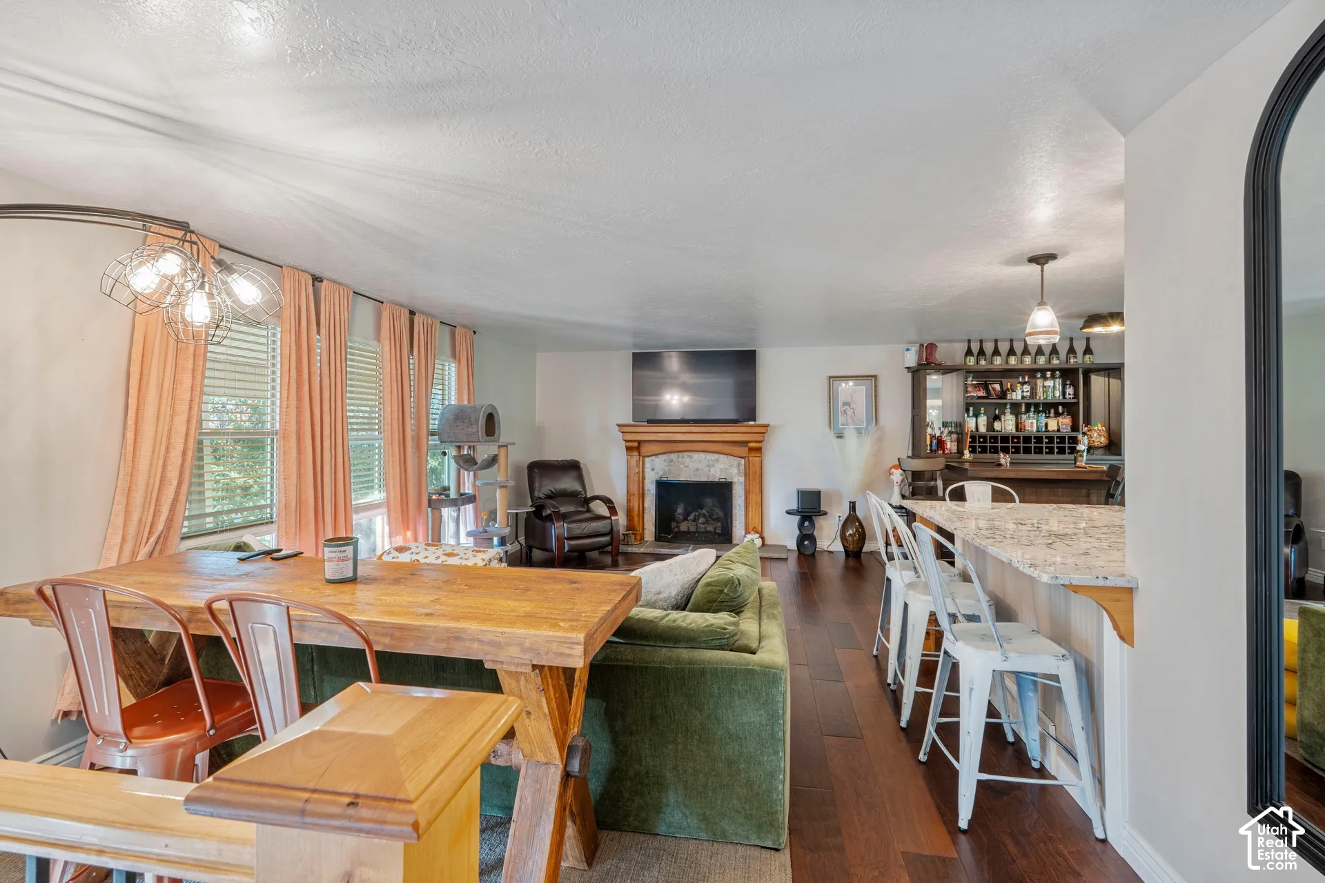 Fireplace with stone-style surround and wood mantel, wood-finish flooring, and built-in wet bar with cabinetry