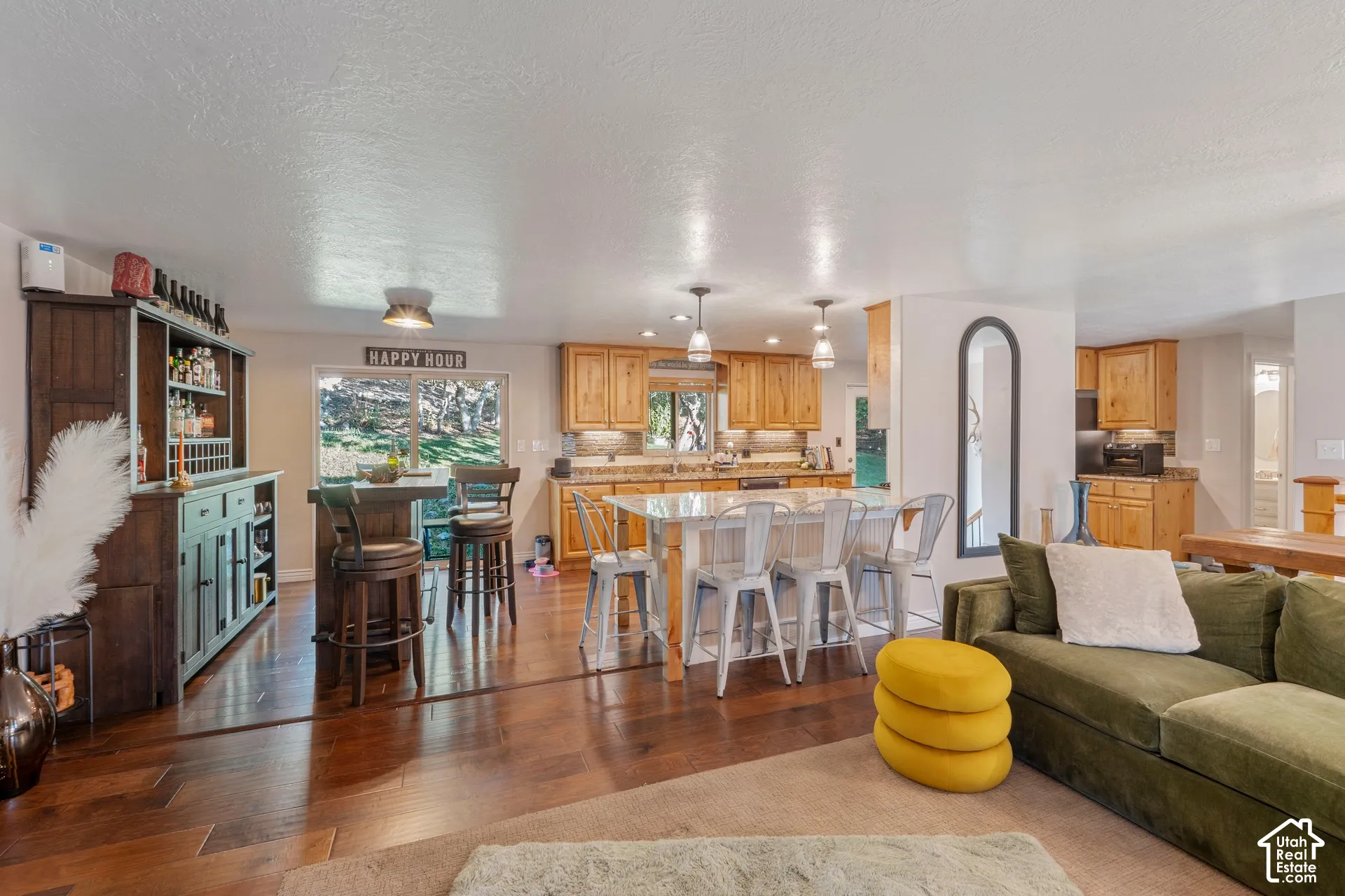 Kitchen featuring light-tone wood cabinetry, stone countertops, central island, wood-finish flooring, and sliding glass doors