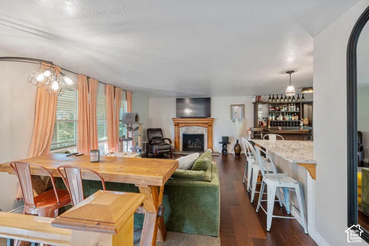 Fireplace with stone-style surround and wood mantel, wood-finish flooring, and built-in wet bar with cabinetry