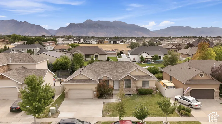 Single-level residence featuring a stone and stucco facade, asphalt shingle roof, attached two-car garage, and mountain range backdrop