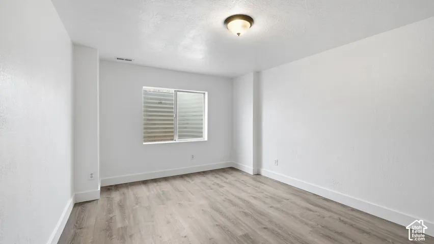 Room interior featuring wood-finish flooring, smooth-textured white walls, and a dome-style flush mount light fixture