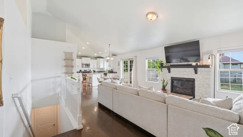 Vaulted ceilings, wood-finish flooring, painted brick fireplace, and white cabinetry