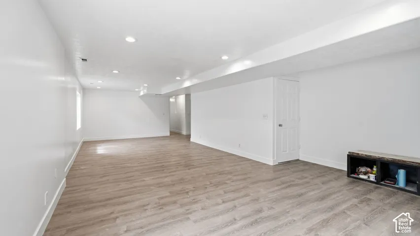 Open-concept interior featuring wood-finish flooring, recessed lighting, and a six-panel interior door