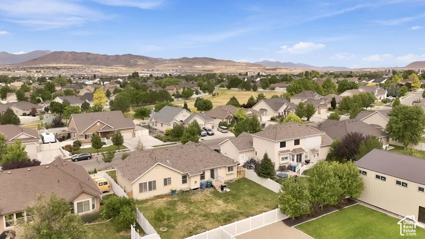 Aerial perspective featuring residential lots with fenced perimeters, paved driveways, and mountain-range scenery