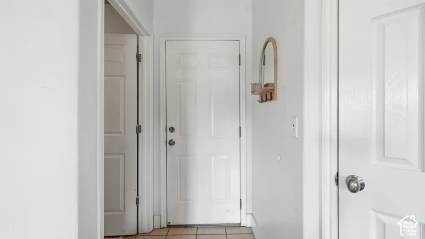 Interior hallway featuring neutral walls, tile flooring, and multiple solid-core panel doors with metallic hardware