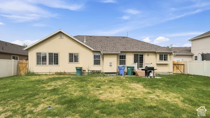 Rear exterior featuring a stucco facade, asphalt shingle roof, sliding glass patio door, and enclosed yard with perimeter fencing