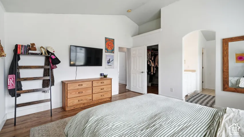 Vaulted ceiling, wood-finish flooring, and an arched entry