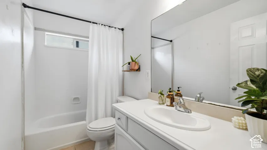 Bathroom featuring a vanity with an integrated basin, a large wall-mounted mirror, and a tub-shower combination with a horizontal window