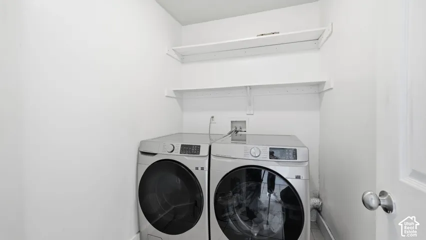 Utility area featuring dual white wall-mounted storage shelves, dedicated laundry hookups, and hard-surface flooring