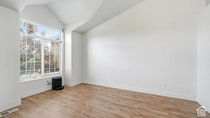 Interior room featuring vaulted ceilings, wood-finish flooring, and a large window assembly