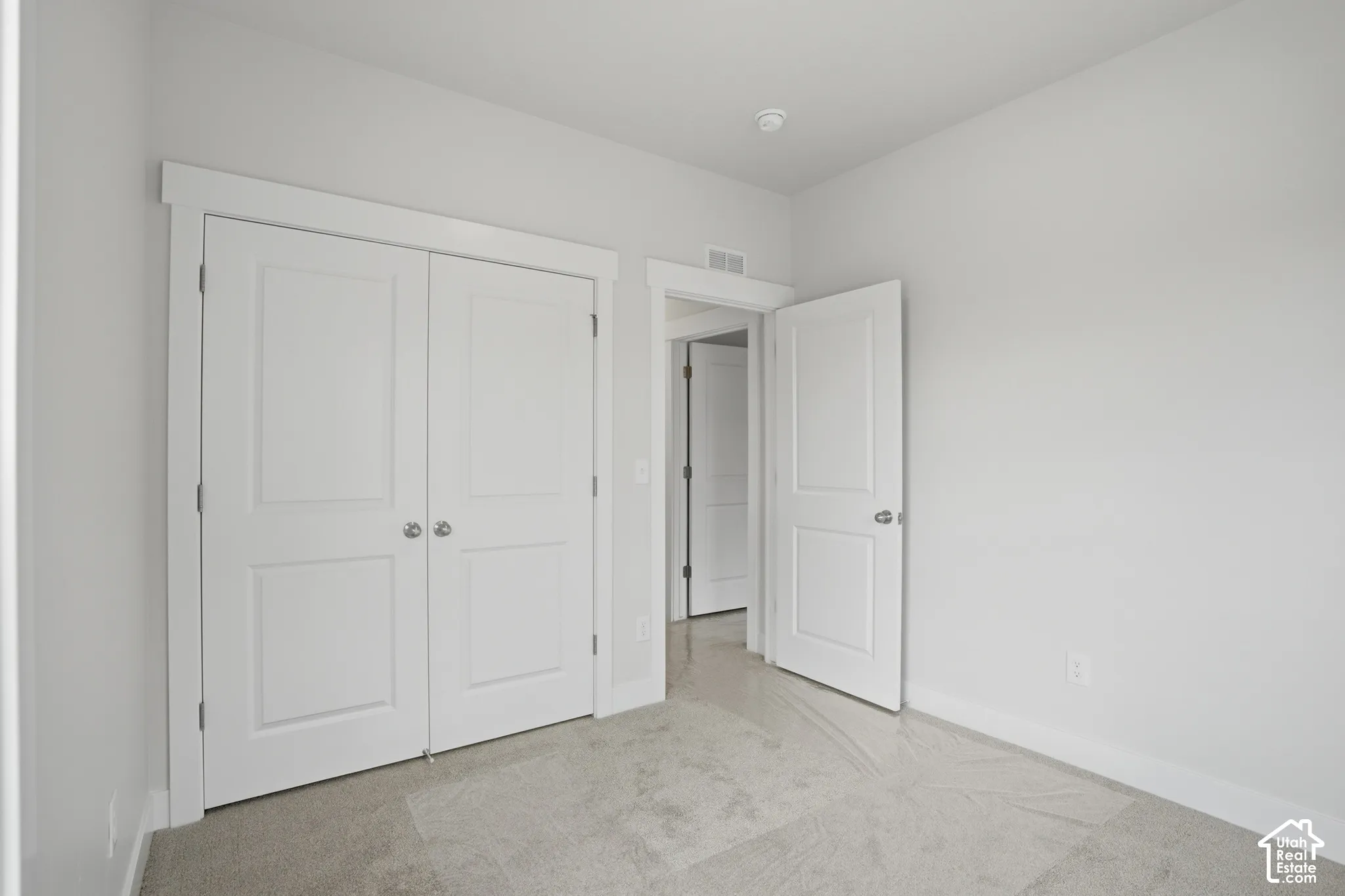 Neutral-toned carpeted flooring, two-panel interior doors, and crisp white door casings