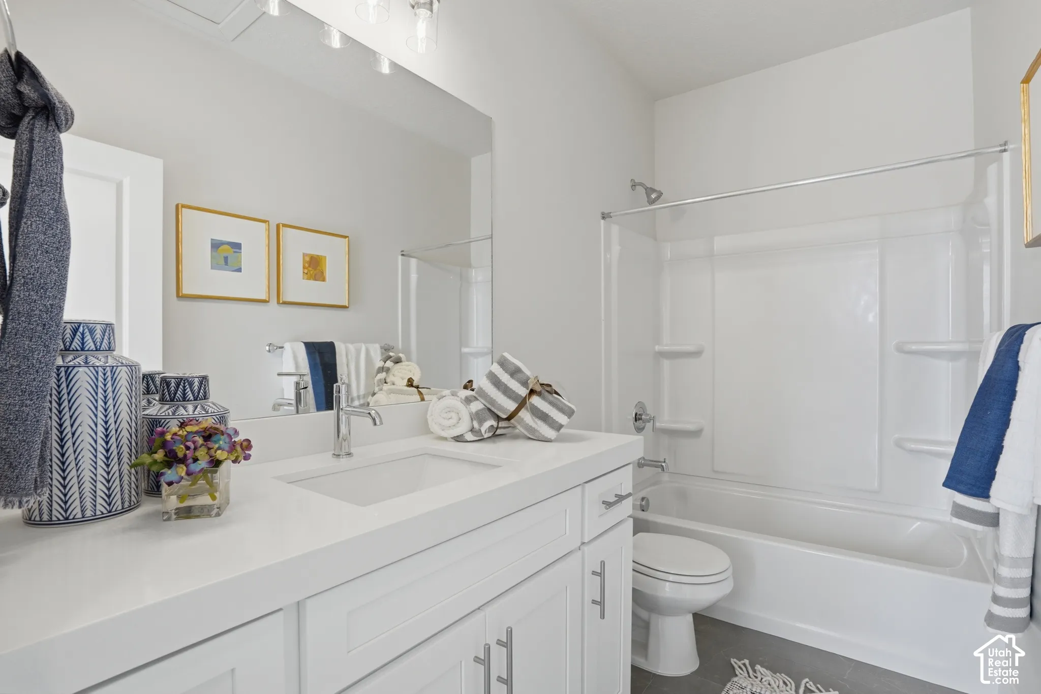 White vanity with a solid-surface countertop, rectangular undermount sink, brushed nickel faucet, large wall-mounted mirror, and a full-height shower and tub surround