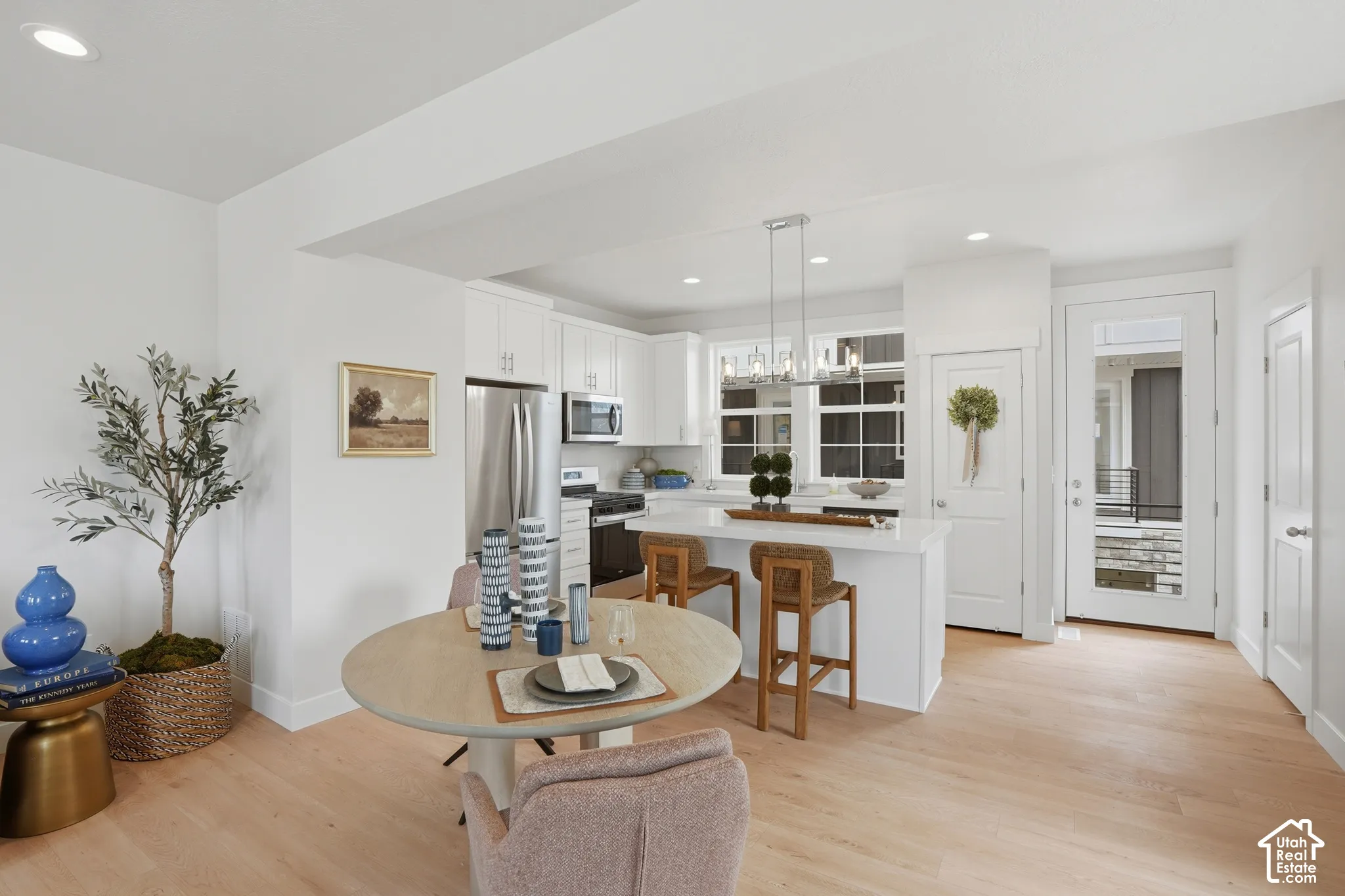 Kitchen featuring white cabinetry, quartz countertops, a central island with bar seating, stainless steel appliances, and wood-finish flooring