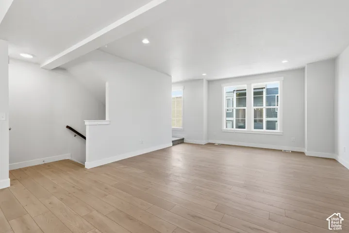 Open-concept interior featuring light wood-finish flooring, recessed lighting, and large windows with white trim