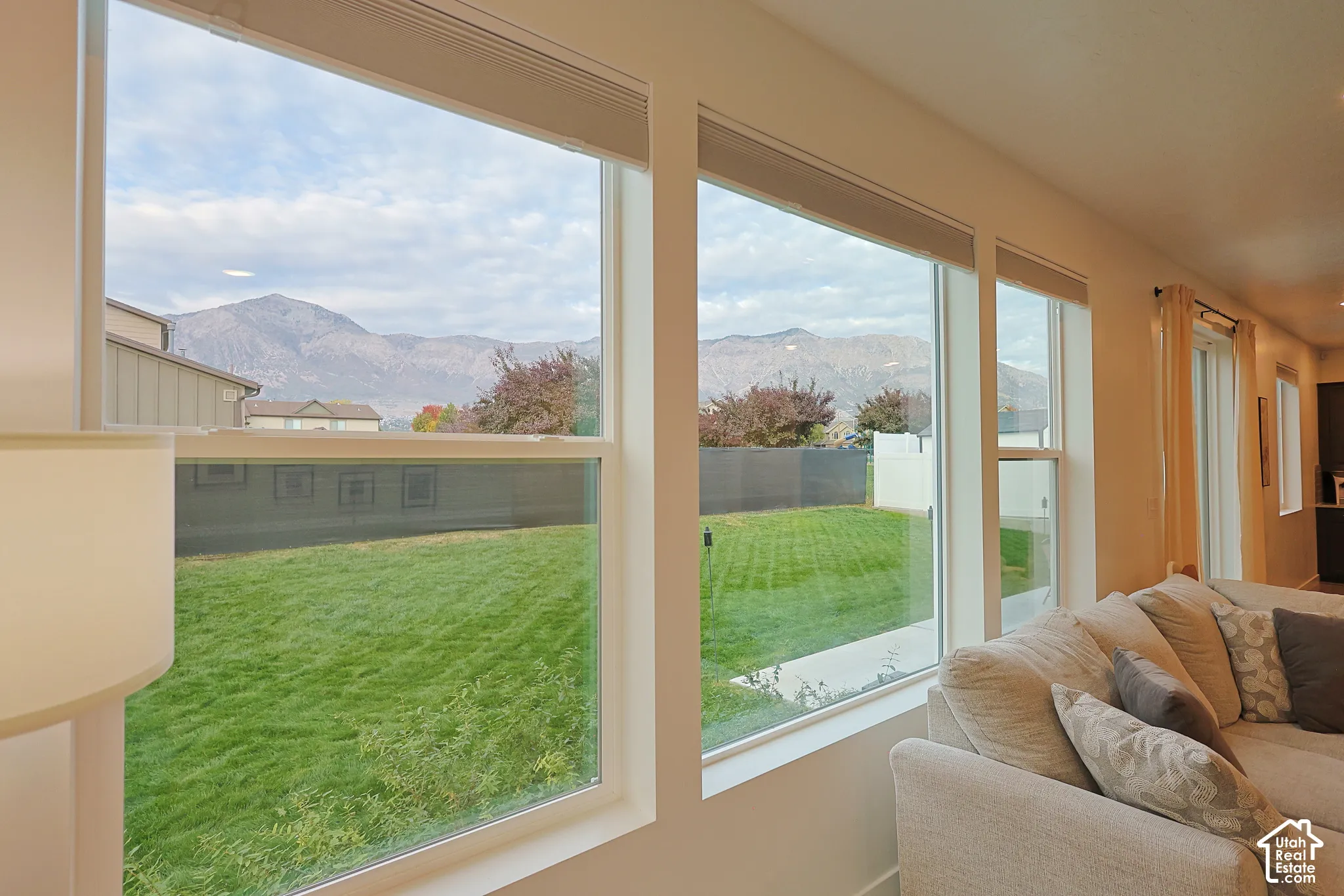 Expansive windows featuring mountain scenery and natural light, complemented by a manicured lawn and white-frame window casings