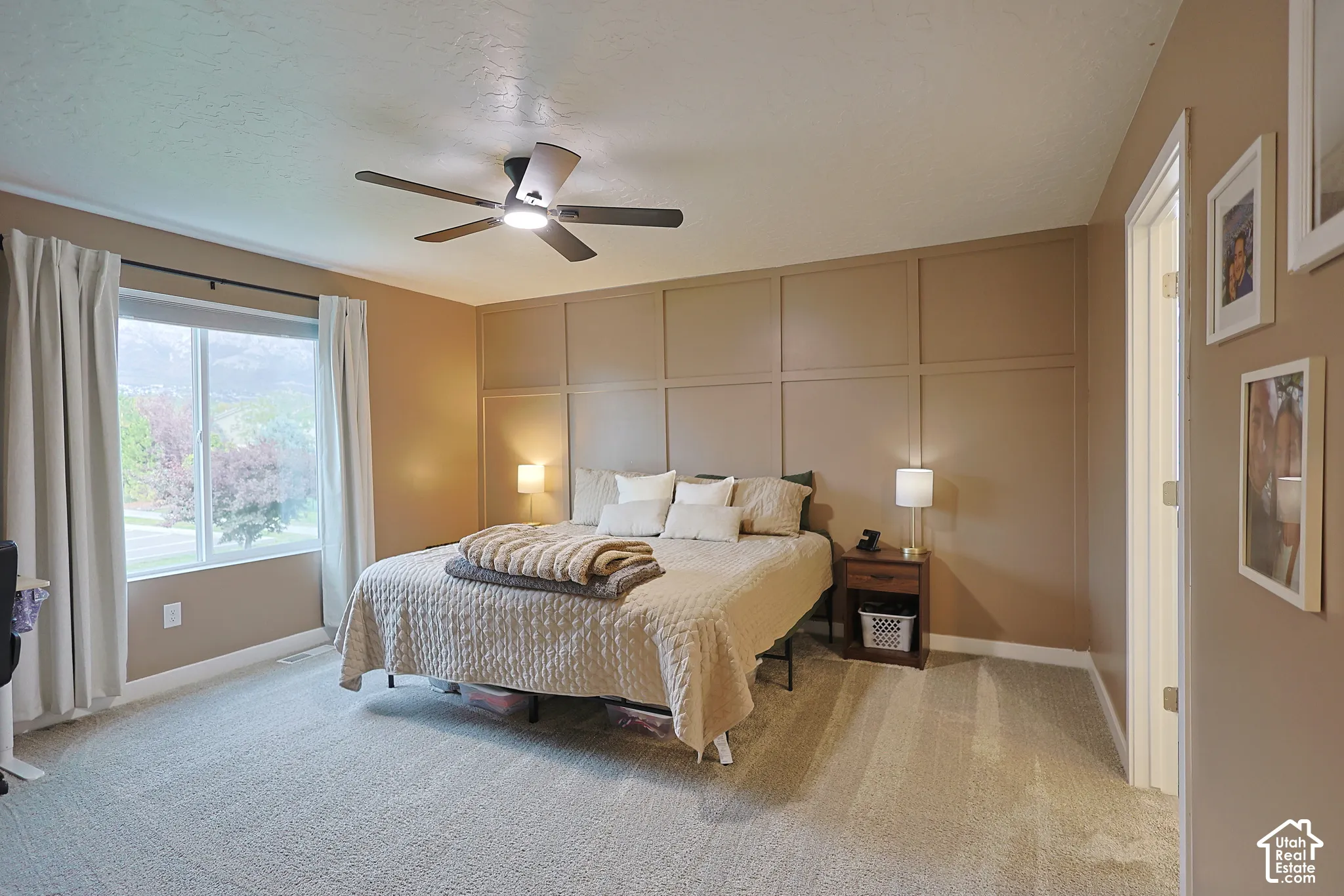 Room featuring a large grid-pattern accent wall, neutral carpeting, and a multi-blade ceiling fan with integrated lighting