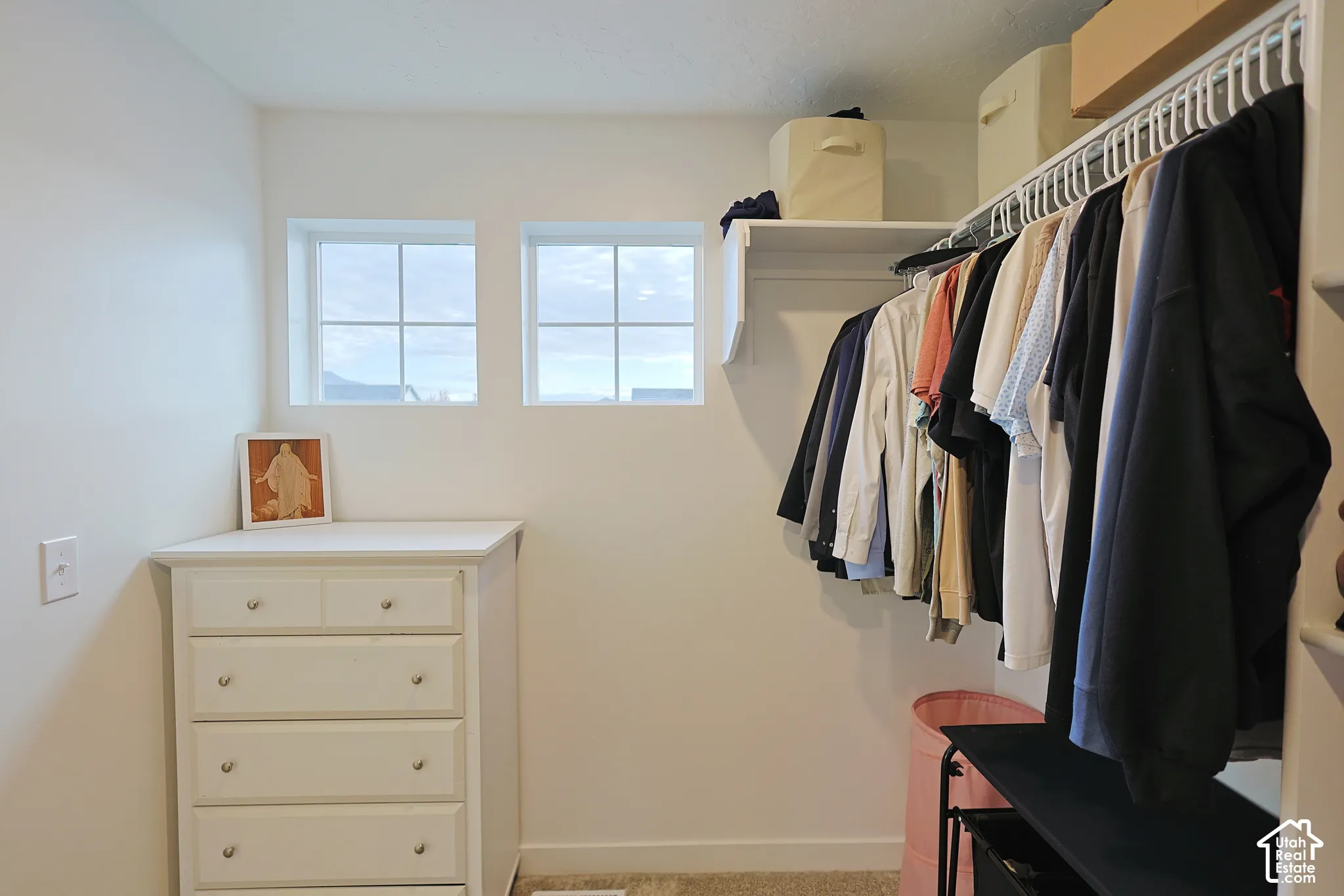 Walk-in closet featuring dual fixed-pane windows and built-in upper shelving with an integrated clothes rod