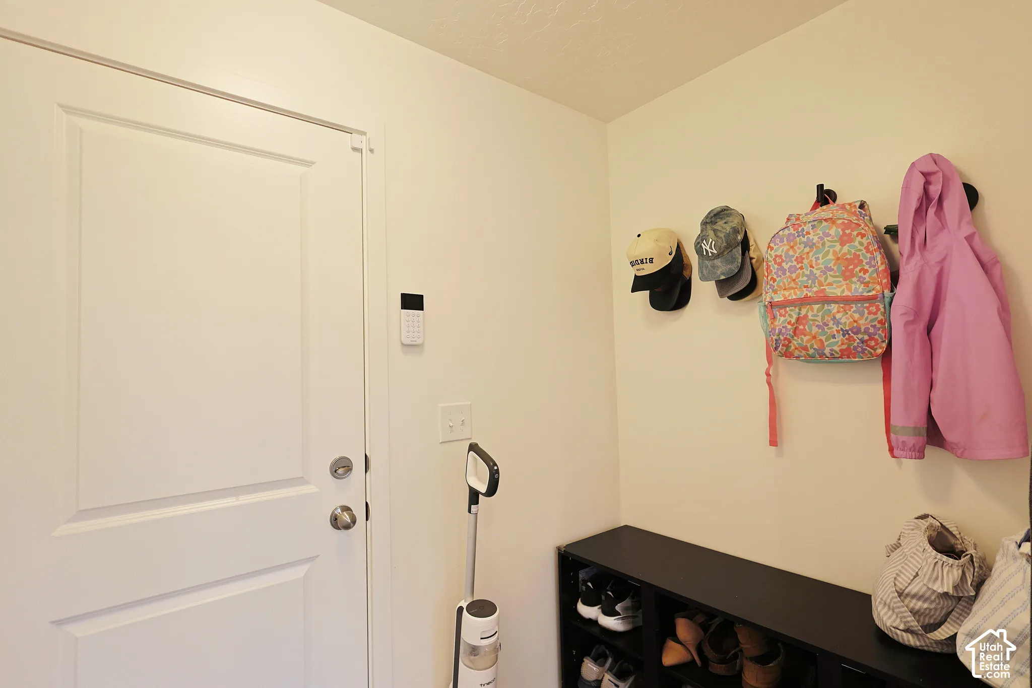 Entry door featuring an integrated security system keypad and wall-mounted metal hooks