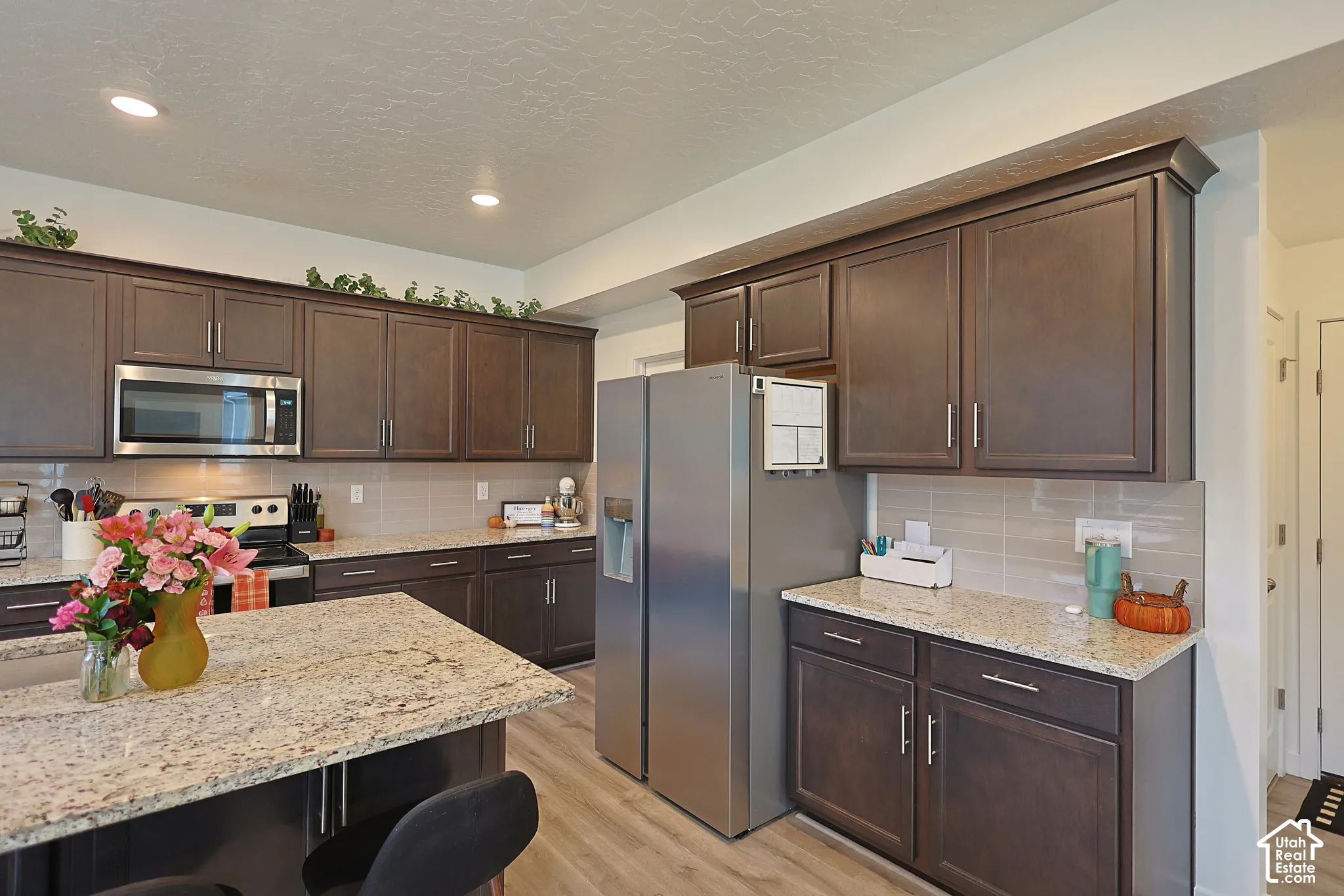 Kitchen featuring dark cabinetry, stone countertops, stainless steel appliances, a center island, and recessed lighting