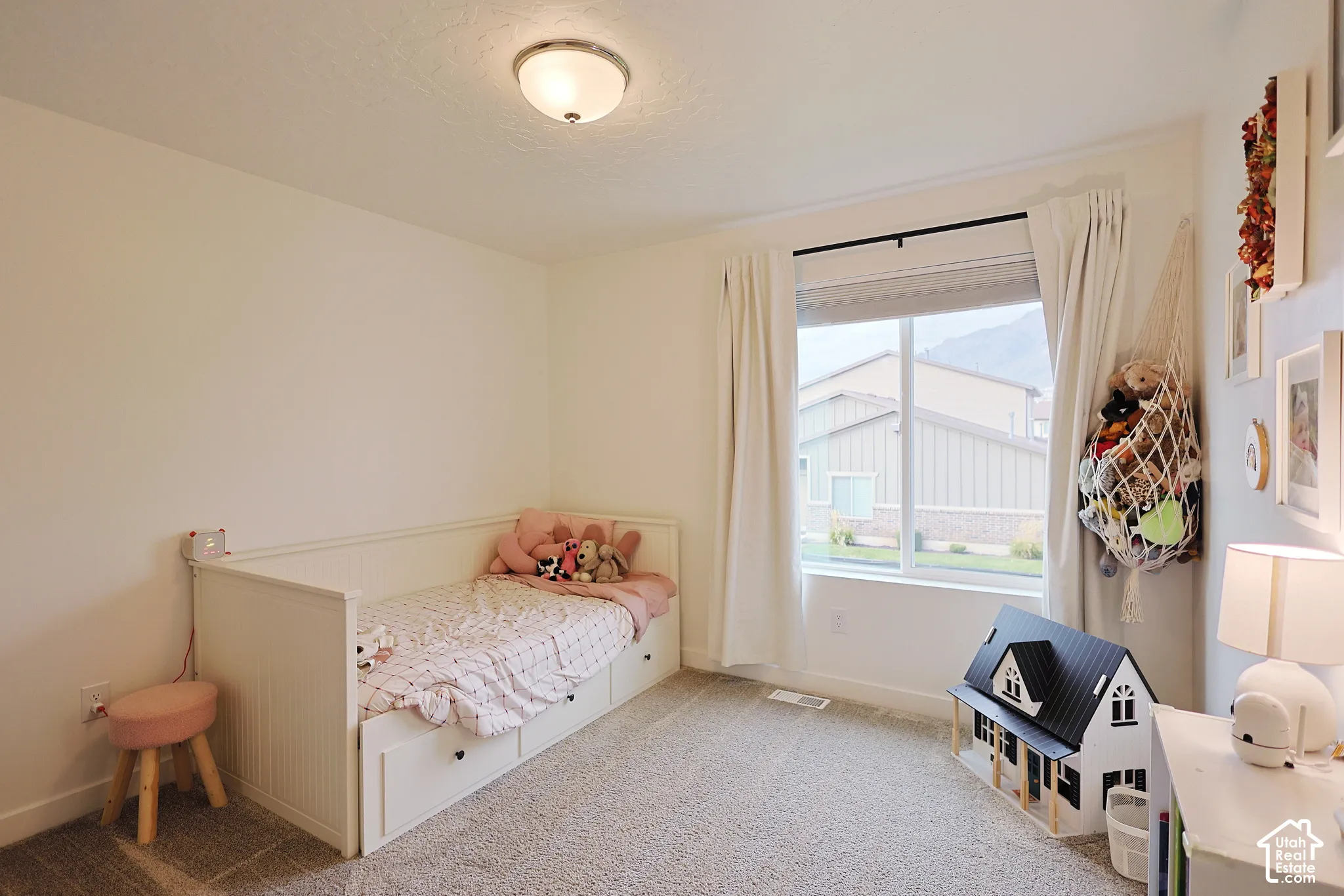 Neutral-toned interior room featuring wall-to-wall carpeting, a large window with natural light, and a flush-mount overhead light fixture
