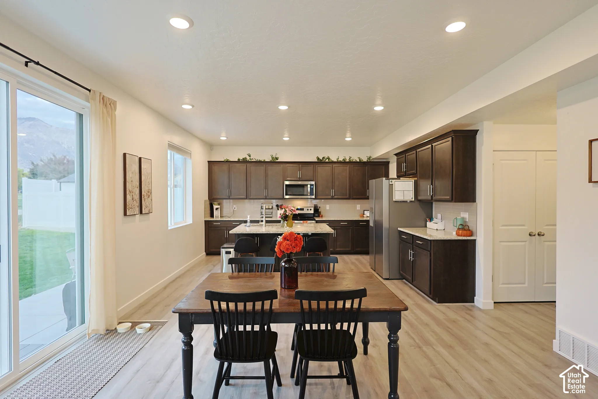 Kitchen featuring dark wood cabinetry, a central island with stone-surface countertop, recessed lighting, and wood-finish flooring