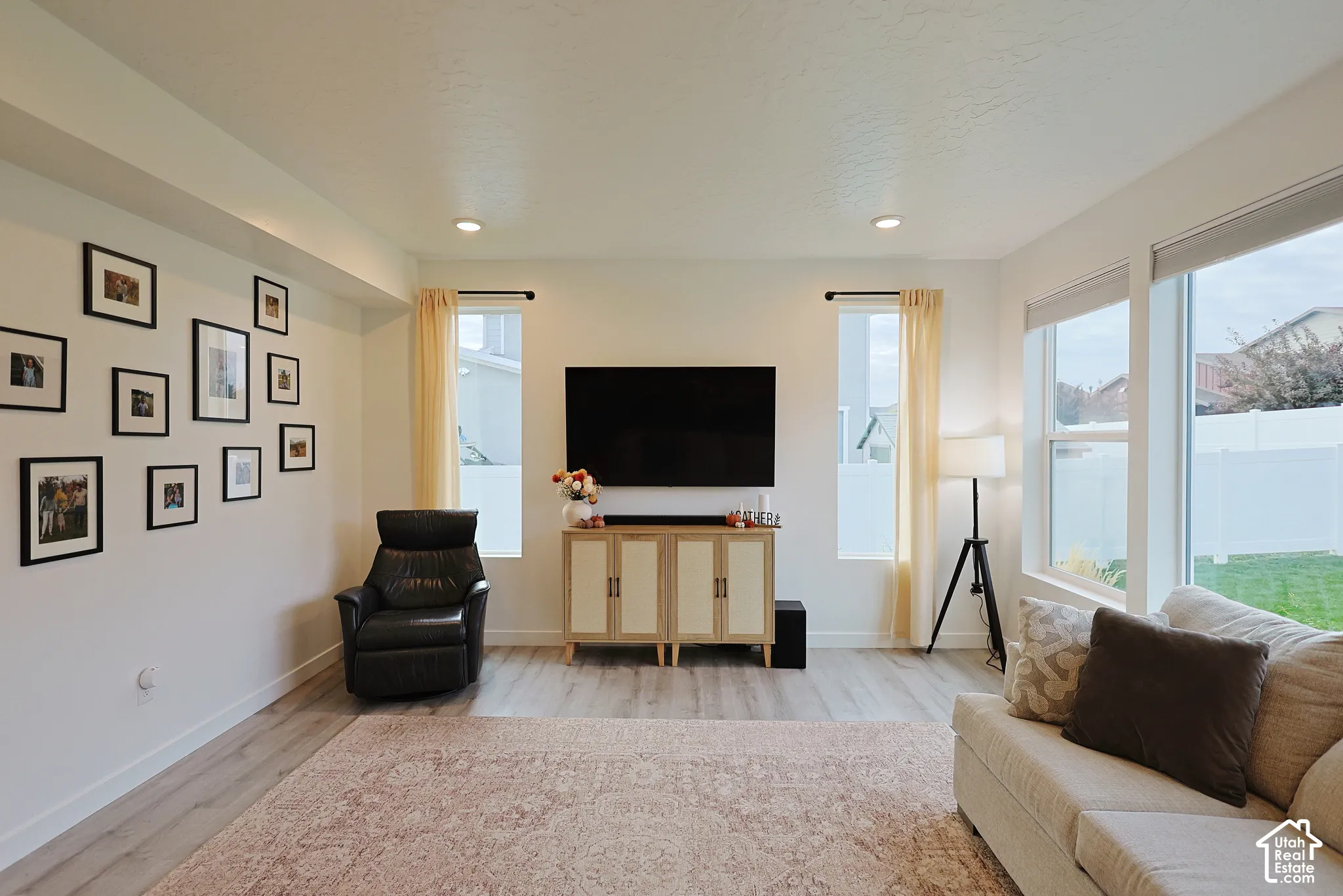 Living area featuring wood-finish flooring, recessed lighting, and expansive windows providing natural light