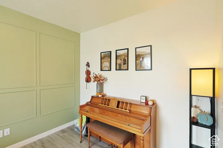 Interior room featuring sage-toned decorative wall molding and wood-finish flooring