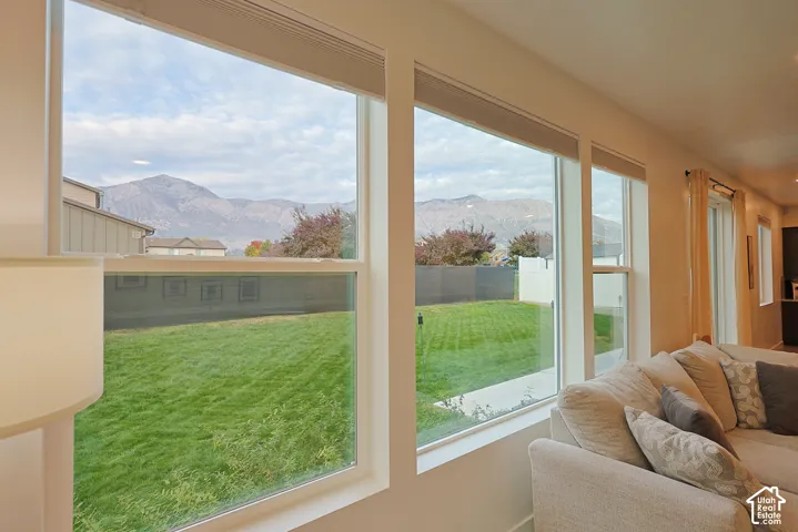 Expansive windows featuring mountain scenery and natural light, complemented by a manicured lawn and white-frame window casings