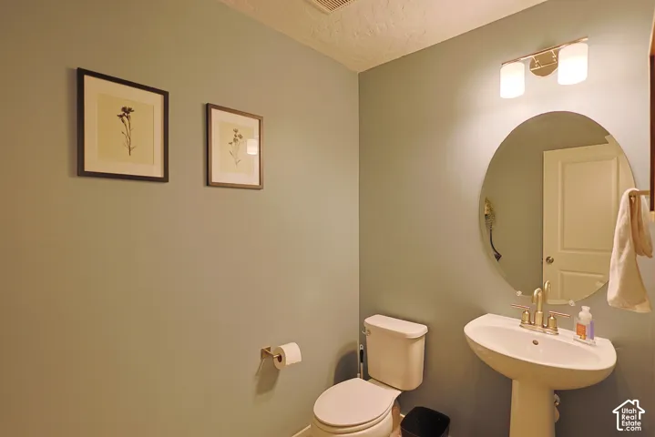 Pedestal sink with brass-finish faucet, oval wall mirror, and two-light vanity fixture