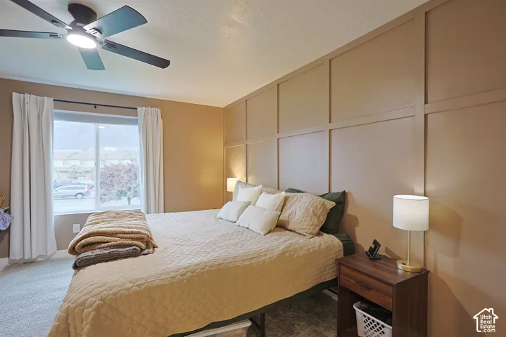 Room featuring a floor-to-ceiling grid-pattern accent wall, neutral carpeting, and a multi-blade ceiling fan with integrated lighting