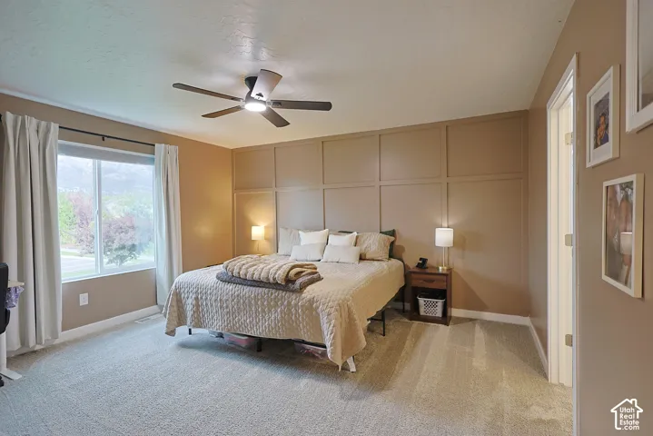 Room featuring a large grid-pattern accent wall, neutral carpeting, and a multi-blade ceiling fan with integrated lighting
