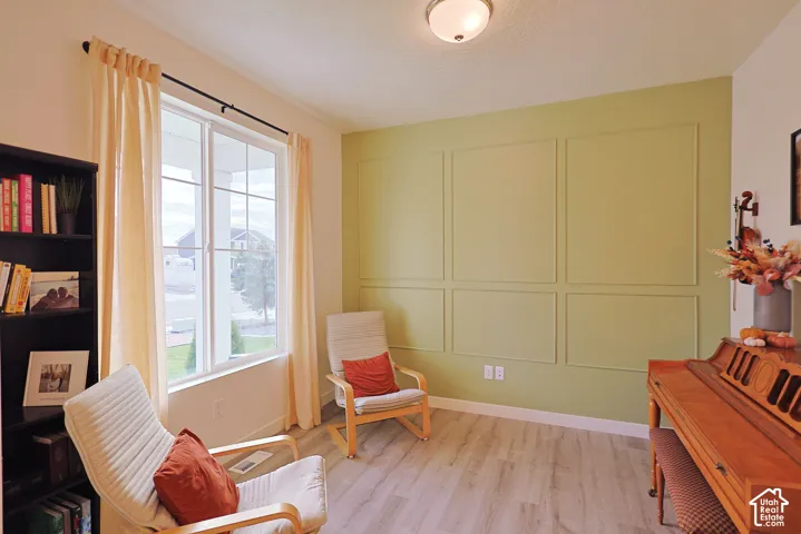 Interior space featuring wood-finish flooring, a wall with decorative applied molding, and a large multi-pane window
