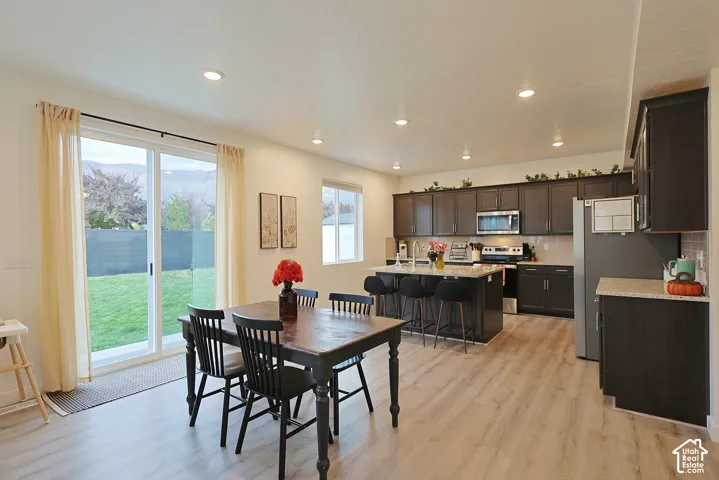 Kitchen featuring dark wood cabinetry, an island with countertop seating, stone-finish countertops, recessed lighting, and wood-finish flooring