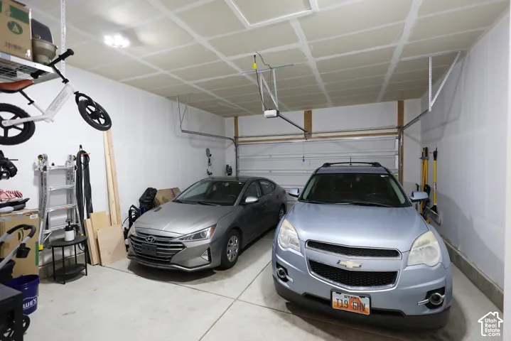 Two-car garage featuring finished drywall, concrete flooring, and an automated overhead door opener