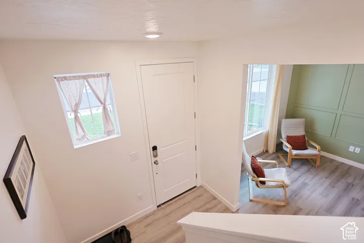 Entryway featuring wood-finish flooring, a solid-panel door, rectangular window, and wall-mounted wainscoting
