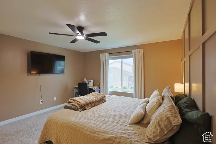 Room featuring wall-paneling detail, neutral paint tones, wall-to-wall carpeting, a multi-blade ceiling fan, and a wide window