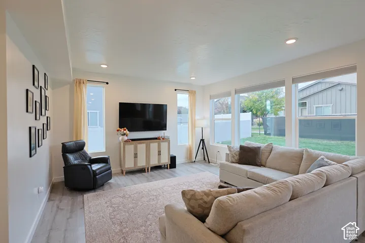 Living area featuring light-toned wood-finish flooring, recessed lighting, and expansive windows providing natural light