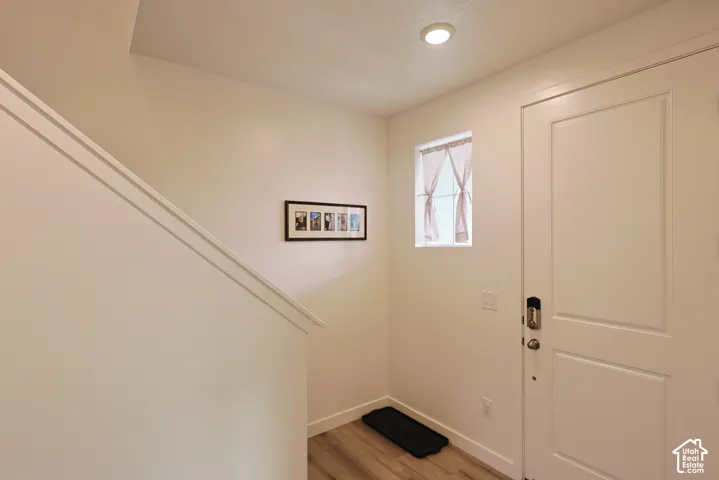 Entryway featuring wood-finish flooring, a solid-panel door with smart-lock hardware, recessed ceiling lighting, and a square window