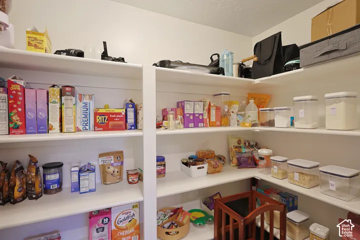 Walk-in pantry featuring white wrap-around shelving with multiple storage tiers