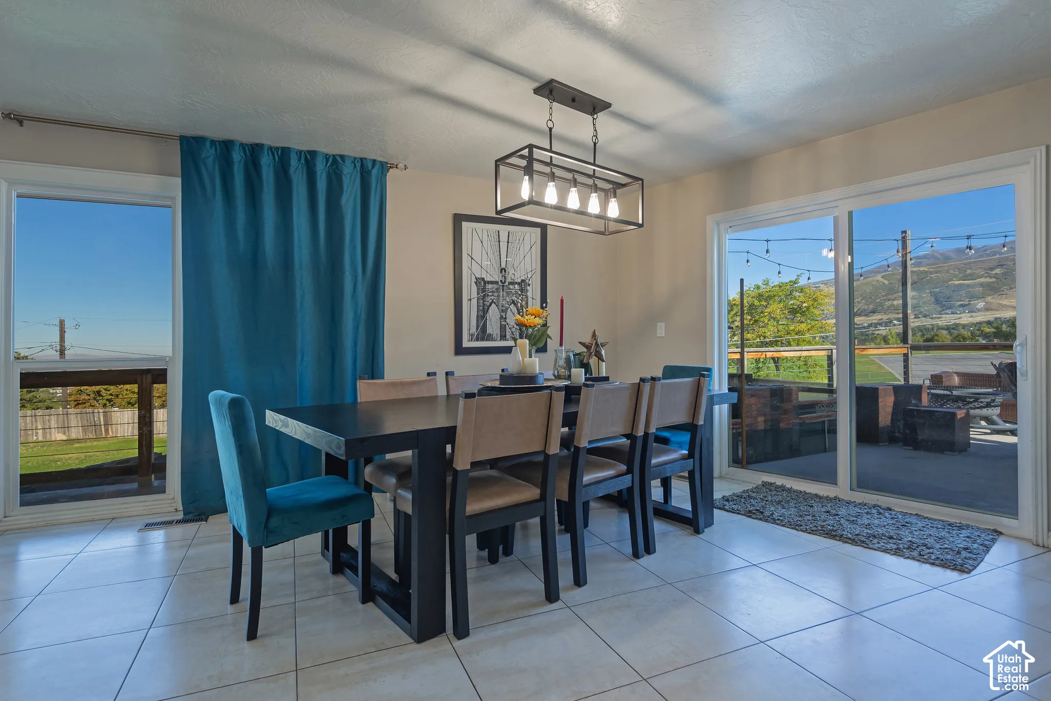 Dining area featuring tile flooring, a rectangular five-light metal chandelier, and dual sliding glass doors providing outdoor access