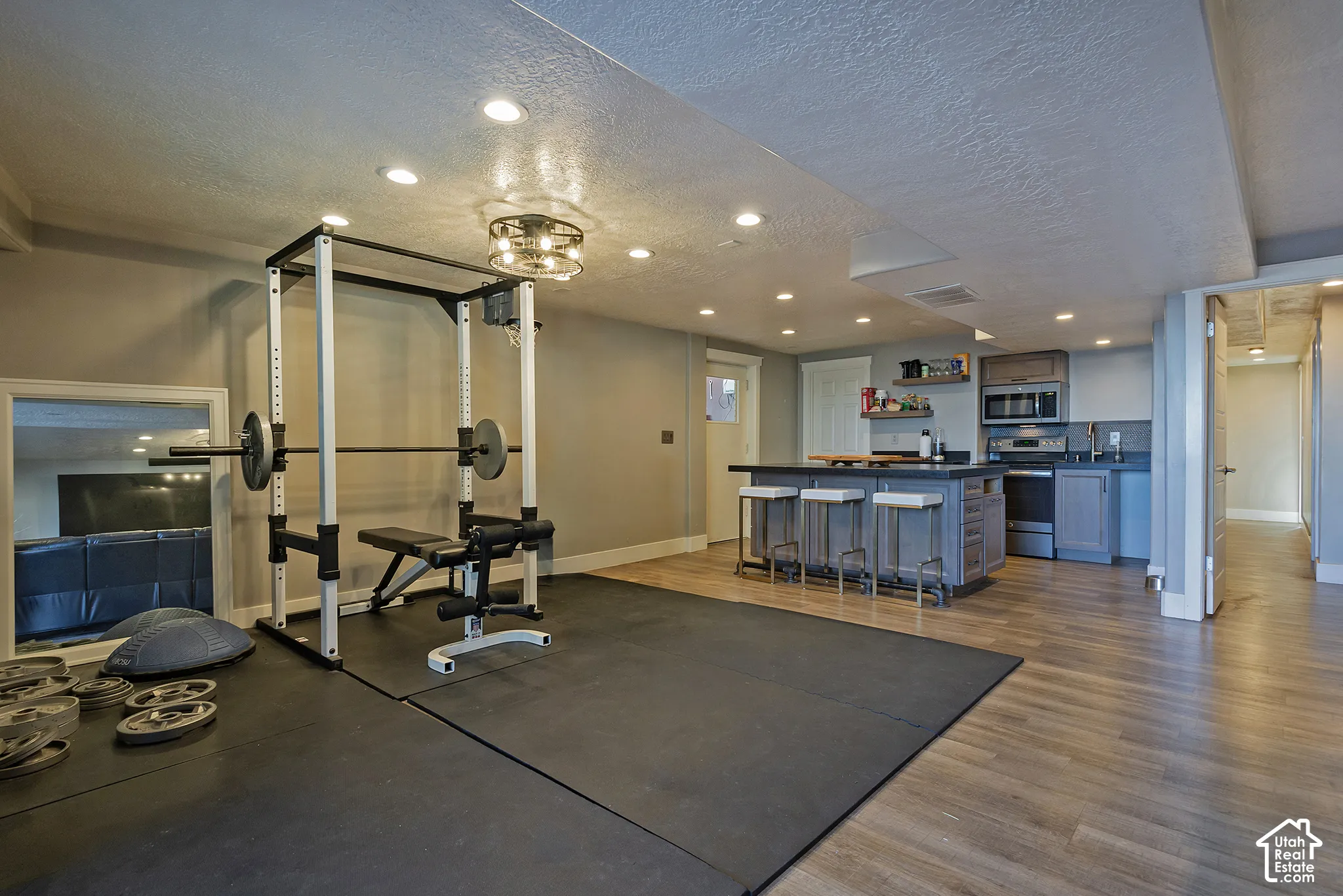Open-concept interior featuring wood-finish flooring, recessed lighting, and a kitchenette with a central island and built-in microwave