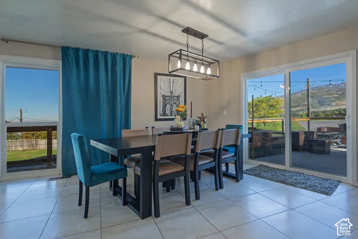 Dining area featuring tile flooring, a rectangular five-light metal chandelier, and dual sliding glass doors providing outdoor access